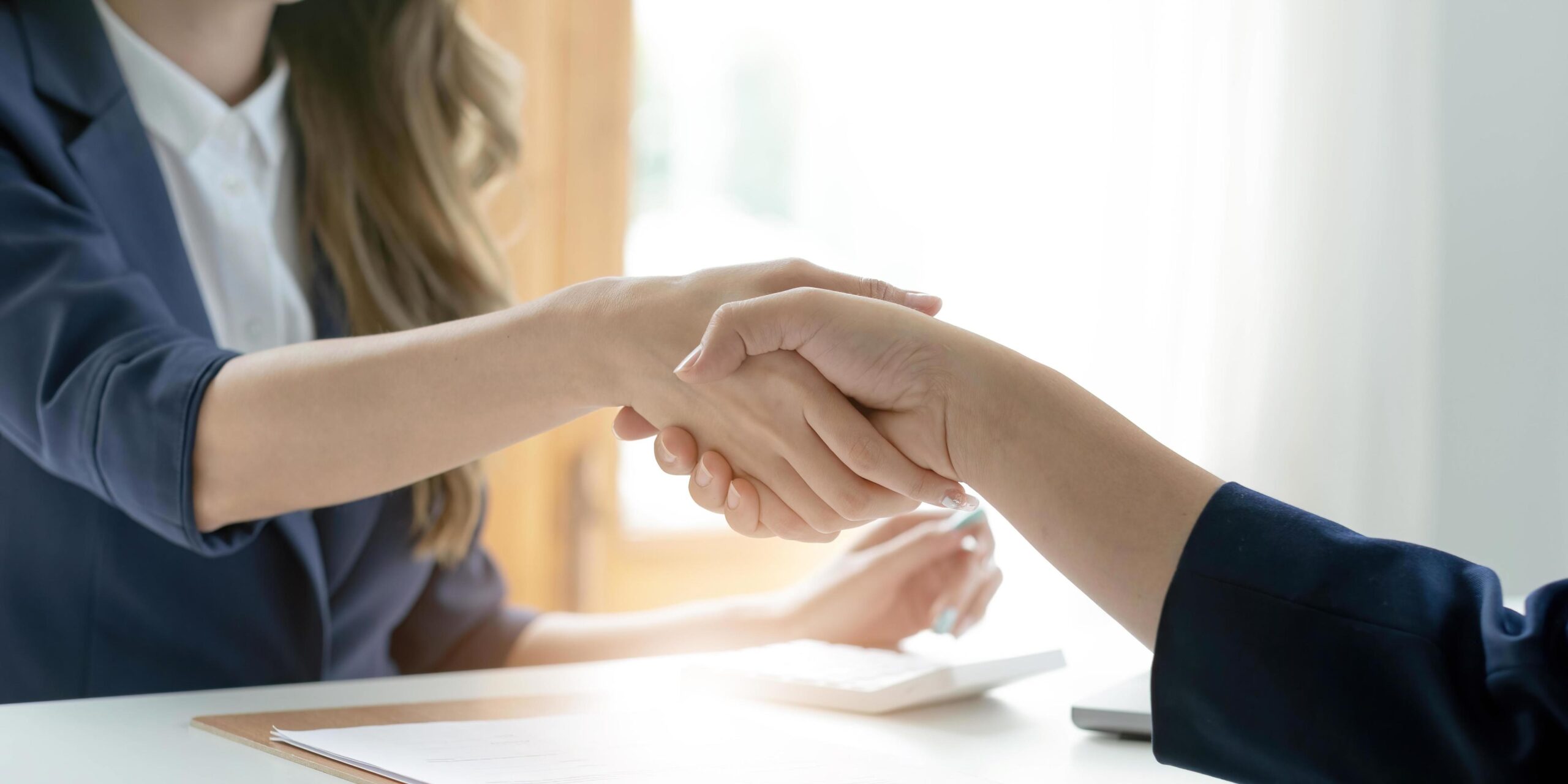 Content & IP Projects closeup of unrecognizable happy businesswoman shaking hands with business partner after signing contract during meeting in office free photo